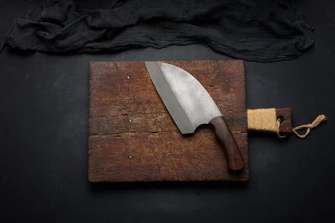 Rectangular empty wooden cutting board and kitchen knife on black table with  Stockfoto's