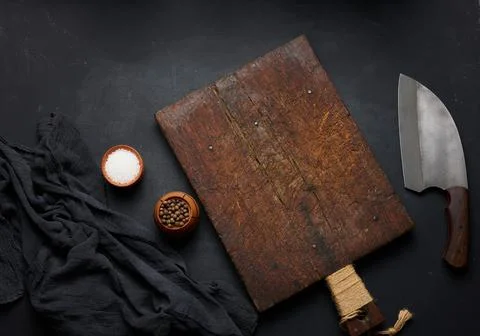 Rectangular empty wooden cutting board and kitchen knife on black table with  Stockfoto's