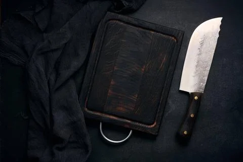 Rectangular empty wooden cutting board and kitchen knife on black table wi... Stockfoto's