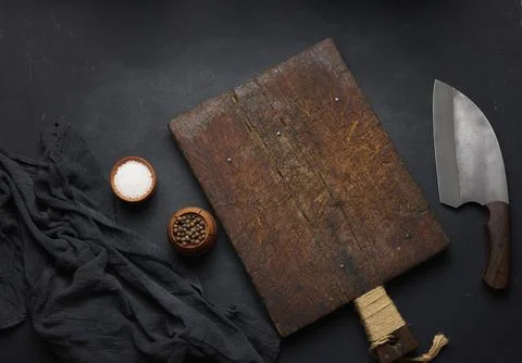 Rectangular empty wooden cutting board and kitchen knife on black table with Stock Photos