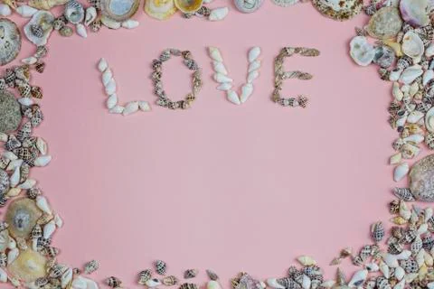 The rectangular frame is lined with seashells and the word love on a pink Stock Photos