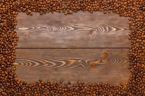 Rectangular frame of many roasted coffee beans on brown wooden surface Stock Photos