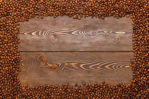 Rectangular frame of many roasted coffee beans on brown wooden surface Stock Photos