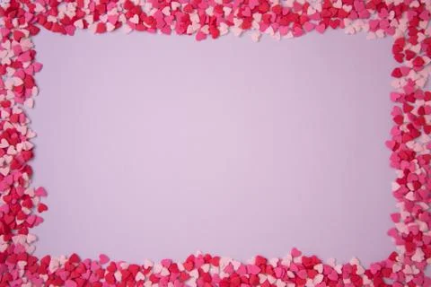 Rectangular frame with small multicolored hearts on a pink background, the co Stock Photos