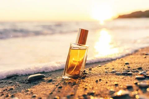 Rectangular glass bottle with golden perfume on wild beach, consecrated by th Stock Photos