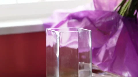 Rectangular Glass Vase Sits Empty as Bouquet of Flowers are Unwrapped and Stock Footage 154384198