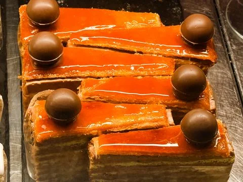 Rectangular layered pastries with glossy glaze and chocolate ball topping. .. Stock Photos