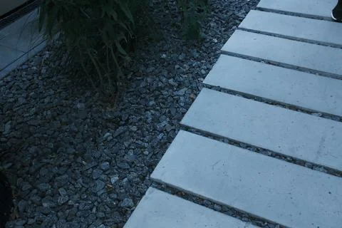 Rectangular light concrete pavers sit next to dark grey decorative gravel in Stock Photos