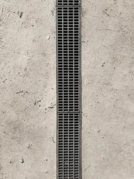 Rectangular metal drain grate set into a dry earth. There is a slight lip a.. Stock Photos
