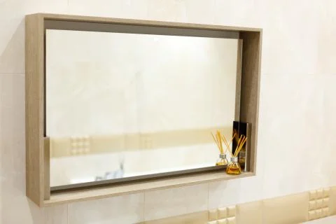 A rectangular mirror in the bathroom hangs on the wall. Stock Photos