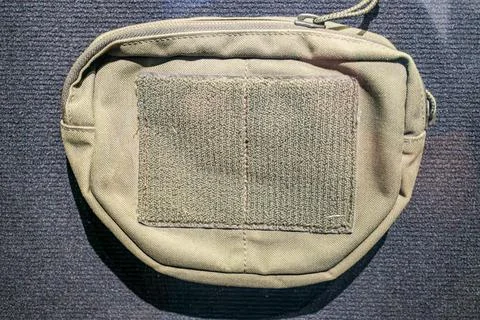 Rectangular, multi-pocketed greenish-brown pouch with textured pattern, likel Stock Photos