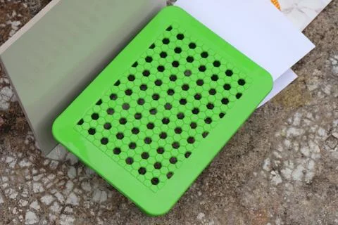 A rectangular pale green board rests near the lime green plastic stool outdoo Stock Photos