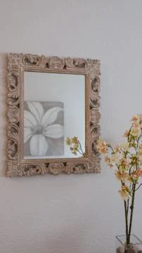 A rectangular patterned mirror reflecting the flowers in the vase and flower  Stock Photos