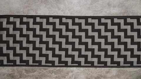 A rectangular piece with a black and gray geometric zigzag pattern on a textured Stock Photos