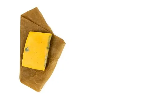 Rectangular piece of moldy cheese on craft paper. Top vew. Stock Photos
