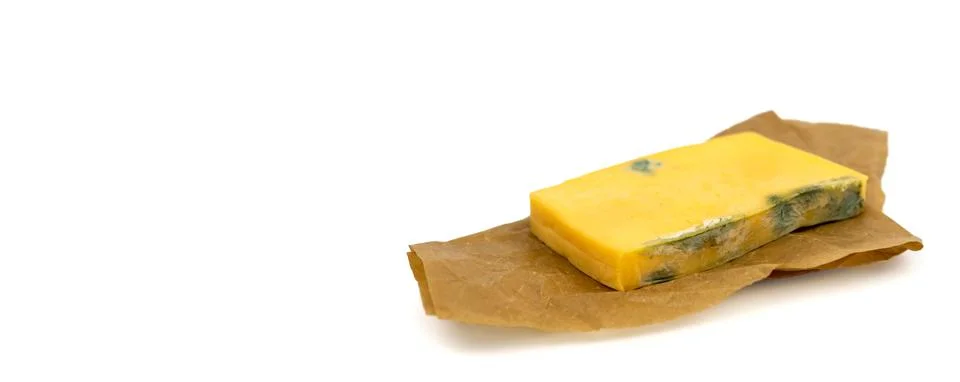 Rectangular piece of moldy cheese on craft paper. Copy space. Side view Stock Photos