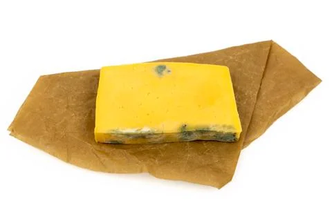 Rectangular piece of moldy cheese on craft paper isolated on white background Stock Photos