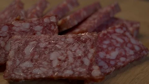 Rectangular pieces of salami on a rotating wooden surface. Sausage close-up. Vídeos de archivo 194932416