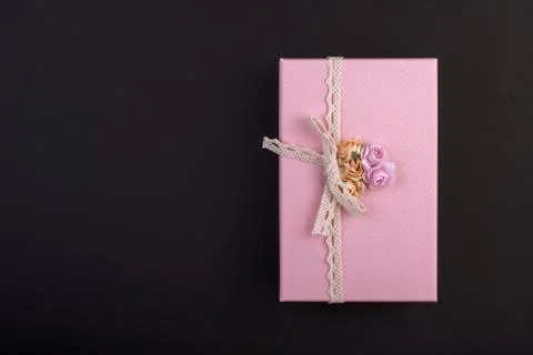 Rectangular pink gift box with bow and flowers on black background, gift on 8 Stock Photos