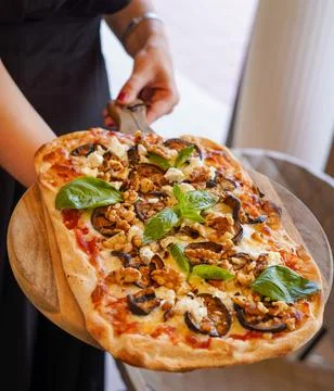 Rectangular pizza with eggplant, walnuts, and feta cheese on a wooden board Photos