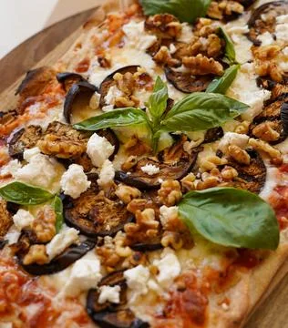 Rectangular pizza with eggplant, walnuts, and feta cheese on a wooden board Foto stock