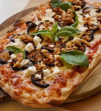 Rectangular pizza with eggplant, walnuts, and feta cheese on a wooden board Foto stock