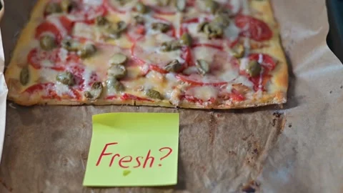 A rectangular pizza sits on a baking tray lined with parchment paper. It has Stock Footage 339096579
