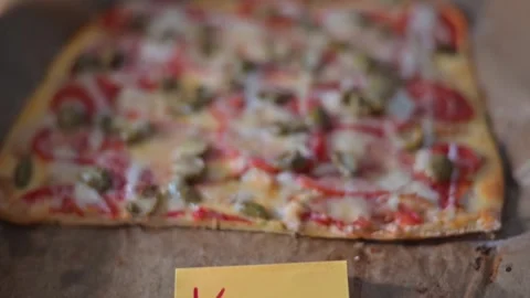 A rectangular pizza sits fresh out of the oven, topped with cheese, olives, and Stock Footage 339096464