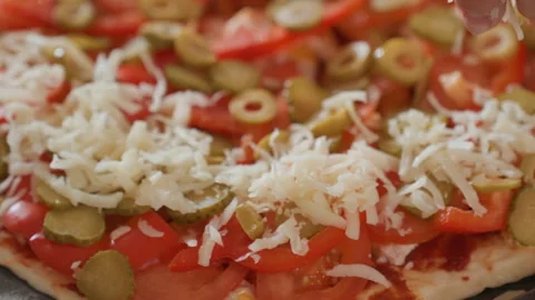 Rectangular pizza topped with tomato slices, green olives, and shredded cheese Stock Footage 343684033