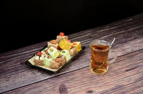 A rectangular plate with an assortment of oriental sweets and a glass cup of 库存照片