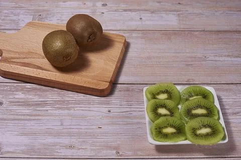 Rectangular plate with cut kiwifruit and several whole Stock Photos