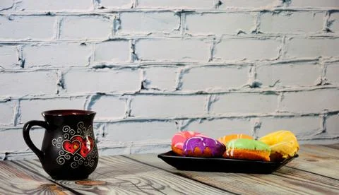 A rectangular plate with five multi-colored donuts and a black ceramic coffee Stock Photos