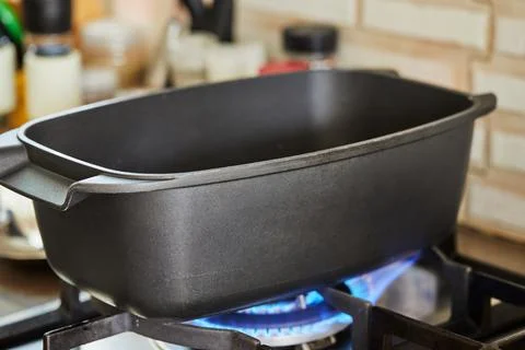 Rectangular pot for cooking and roasting meat stands on fire on gas stove Stock Photos