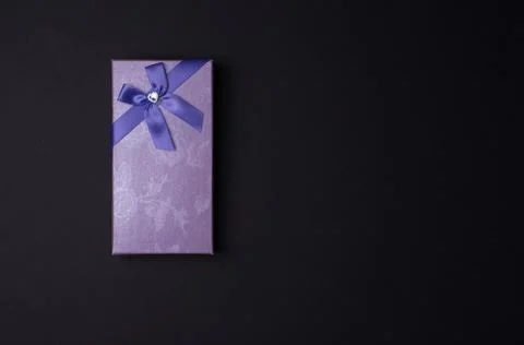 Rectangular purple gift box with bow on black background, top view Stock Photos