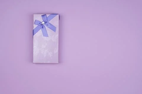 Rectangular purple gift box with bow on purple background, top view Stock Photos