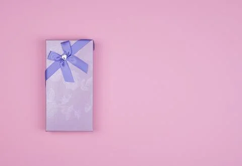 Rectangular purple gift box with bow on pink background, top view Stock Photos