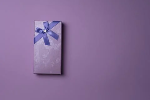 Rectangular purple gift box with bow on purple background, top view Stock Photos