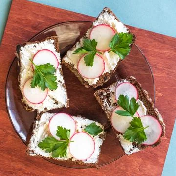 Rectangular sandwiches with butter, cheese and radish on a black plate Stock Photos