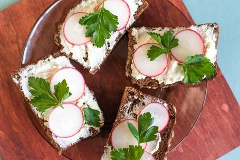 Rectangular sandwiches with butter, cheese and radish on a black plate Stock Photos