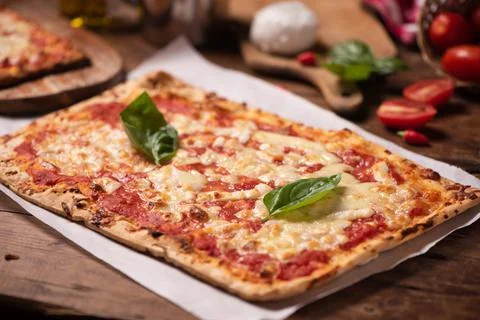 Rectangular shape home made pizza on rustic table with mozarella tomato and b Stock Photos