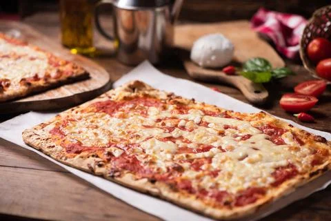 Rectangular shape home made pizza on rustic table with mozarella tomato and b Stock Photos