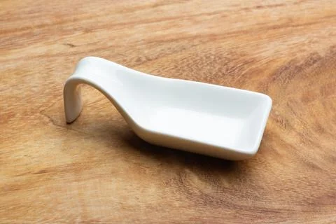 Rectangular shape white ceramic spoon on a wooden table Stock Photos