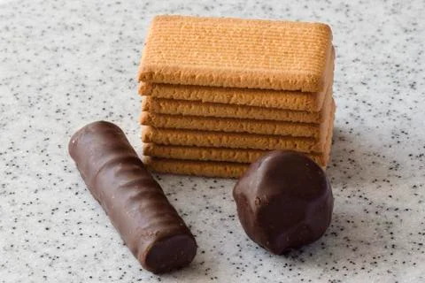 Rectangular shortbread cookies and chocolates on a light marble top. Stock Photos