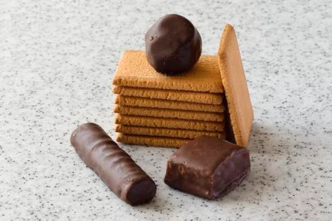 Rectangular shortbread cookies and chocolates on a light marble top. Stock Photos