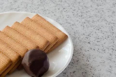 Rectangular shortbread cookies and chocolates on a white saucer. Stock Photos