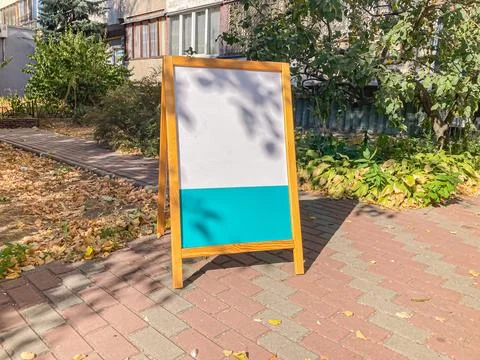 A rectangular sign with Cyrillic text, likely Russian, stands on a street a.. 스톡 사진