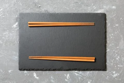 Rectangular slate plate with chopsticks for sushi on black marble background 库存照片