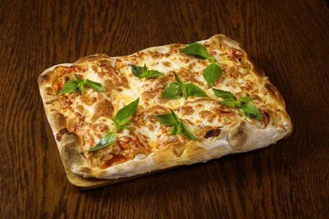 Rectangular slice of pizza lies on a wooden table Stock Photos