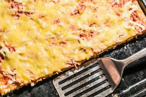 Rectangular slice of pizza on the shoulder, cooked at home, dish on a black t Stockfoto's