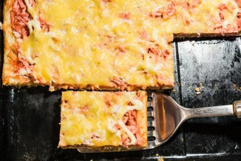 Rectangular slice of pizza on the shoulder, cooked at home, dish on a black t Stockfoto's